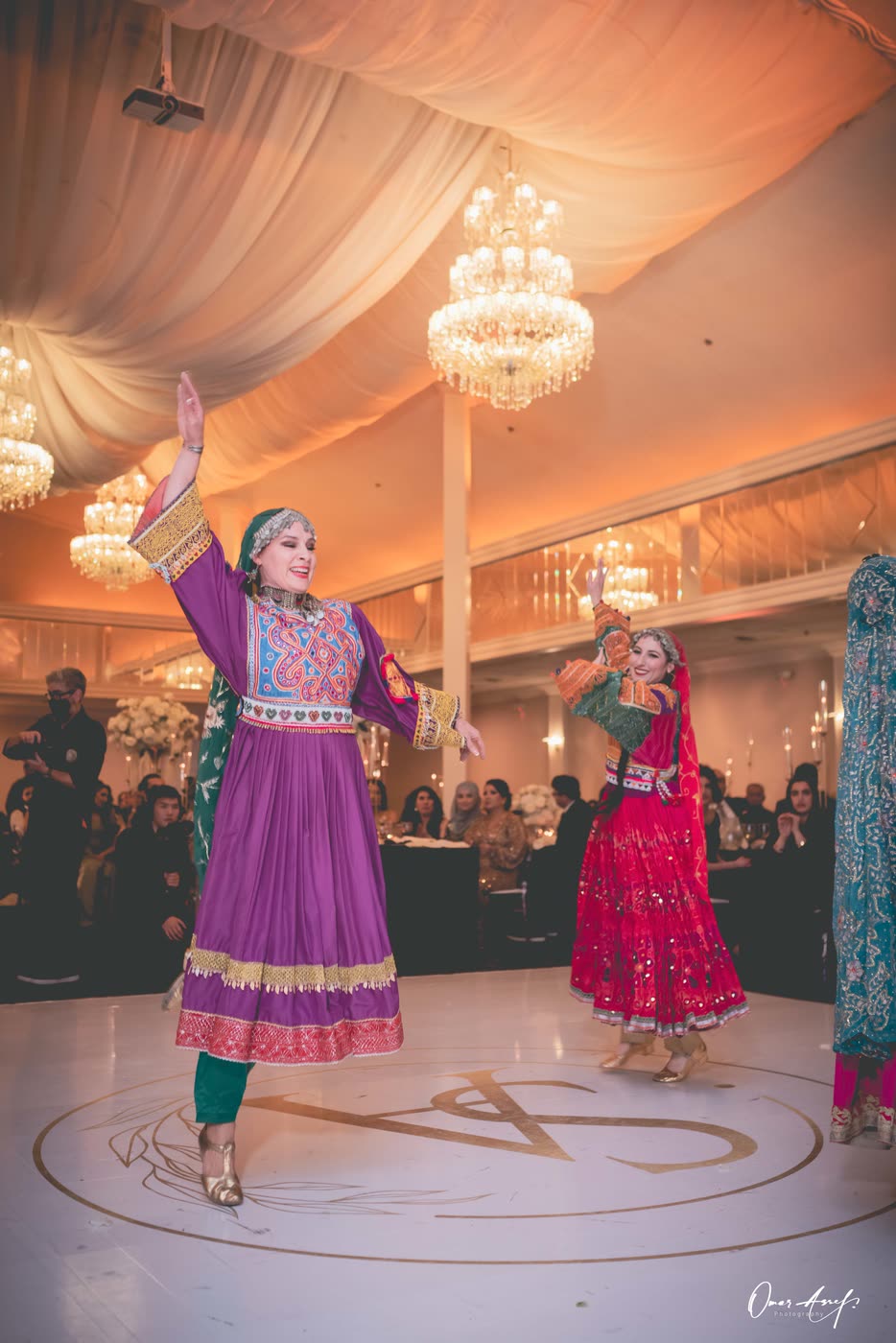A smiling dancer in purple raising one arm