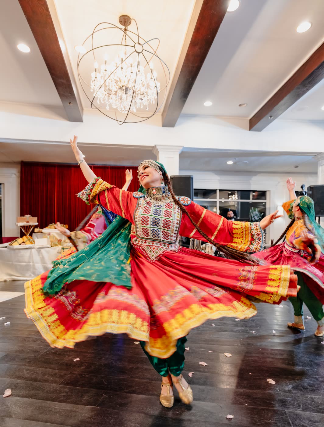 A dancer in red and gold spinning beneath a chandelier